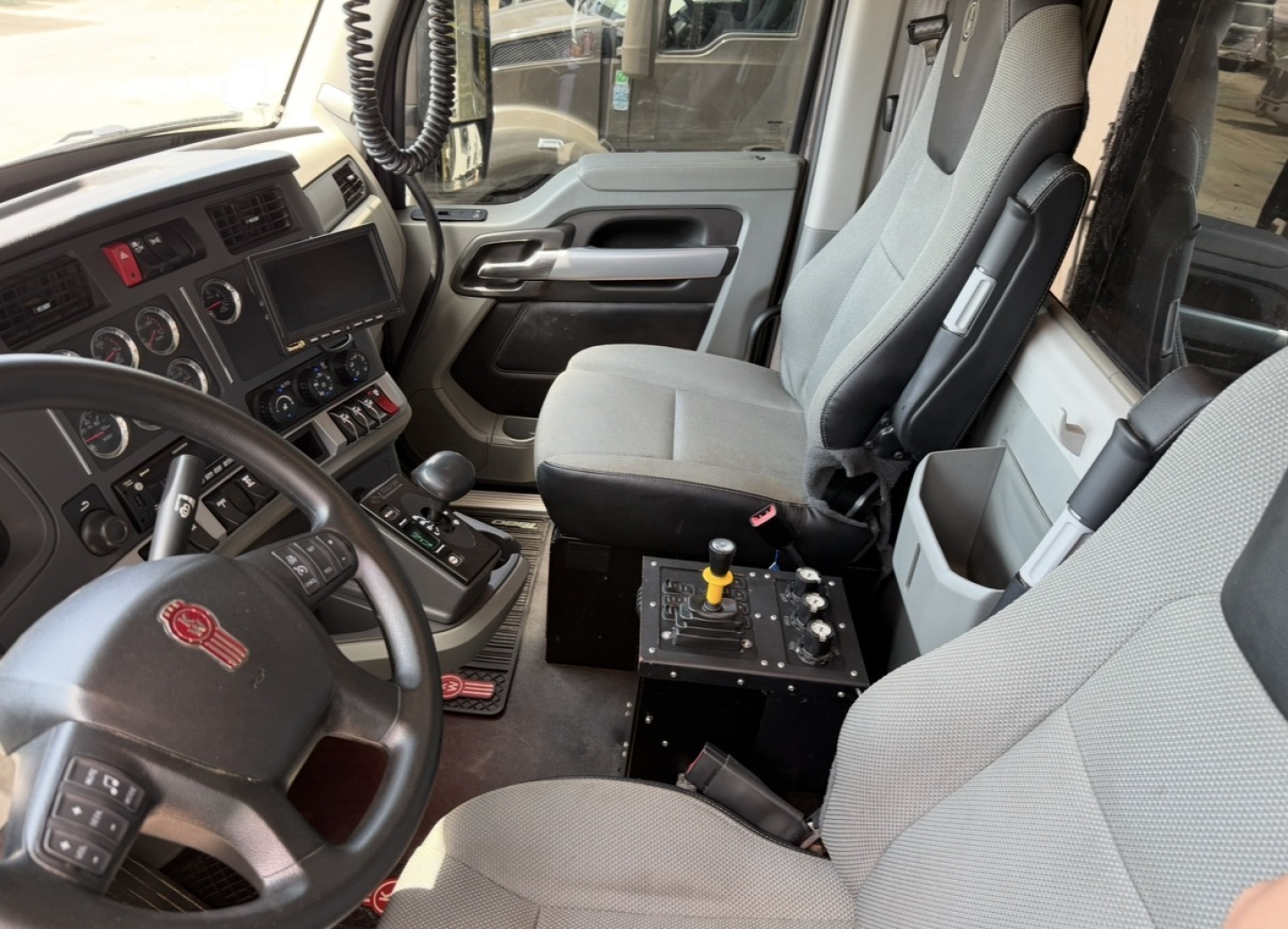 Kenworth T880 truck interior showing driver seat and center console with control levers and dashboard text