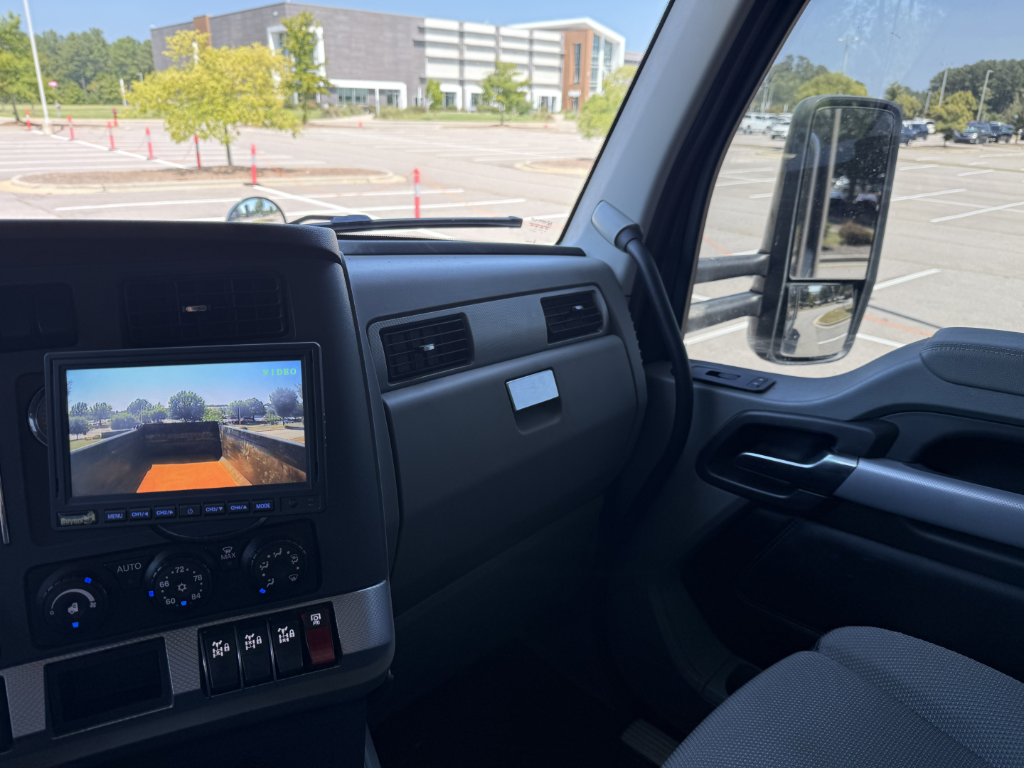 Interior of a 2022 Kenworth T880 cab showing dash with infotainment screen and steering wheel, side mirror, and center console area.