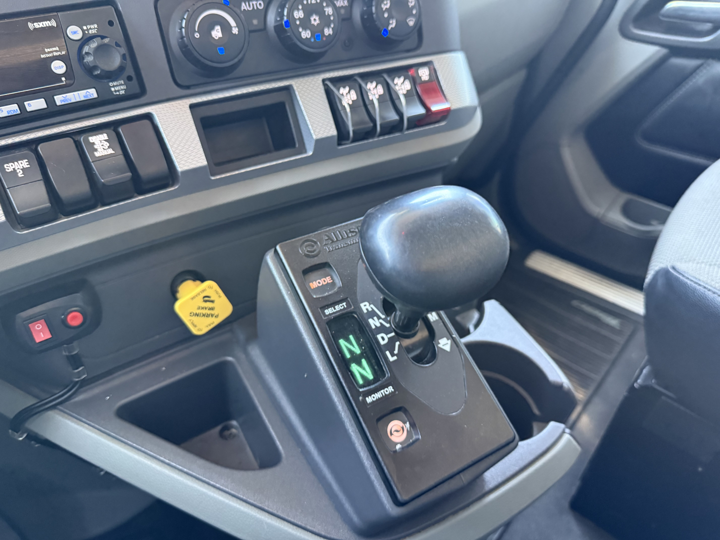 Kenworth T880 interior view showing automatic shifter with N and D indicators, dashboard gauges, and yellow hydraulic/engine auxiliary warning cap visible.