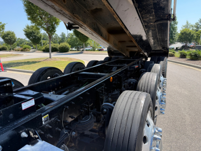 Kenworth T880 dump truck chassis under raised dump bed showing dual rear axles and frame rails.