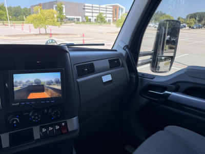 Interior of a 2022 Kenworth T880 cab showing dash with infotainment screen and steering wheel, side mirror, and center console area.