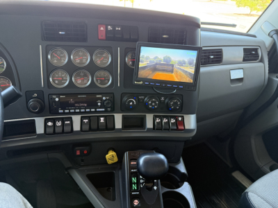Cab interior of a 2022 Kenworth T880 showing cluster gauges, overhead console, touchscreen display, gear shifter, and control switches.