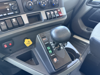 Kenworth T880 interior view showing automatic shifter with N and D indicators, dashboard gauges, and yellow hydraulic/engine auxiliary warning cap visible.