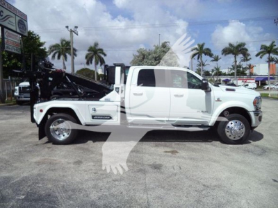 Ram 2500/3500 heavy-duty tow-truck variant in white, side profile view with a winch bed and dual rear wheels, Ram badges visible.
