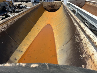 Dump trailer chute interior with yellow-orange coating and wear marks, showing the curved walls and central trough of a Ranco ED26-34