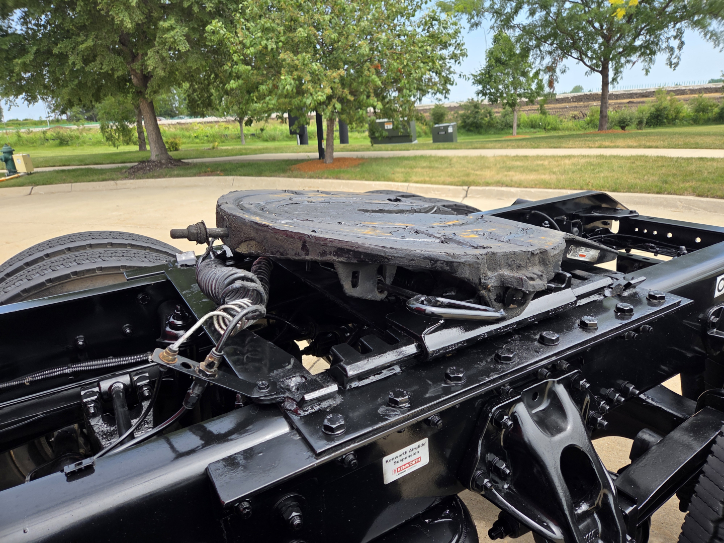 Tractor-trailer truck chassis showing fifth wheel plate and frame rails with wiring harness near cab area.