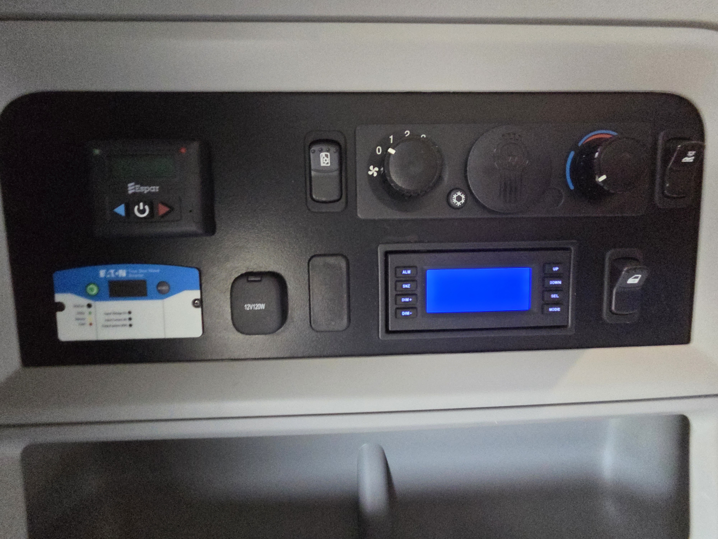 Kenworth T680 dash panel showing control knobs and blue display screen with steering area and card slot.