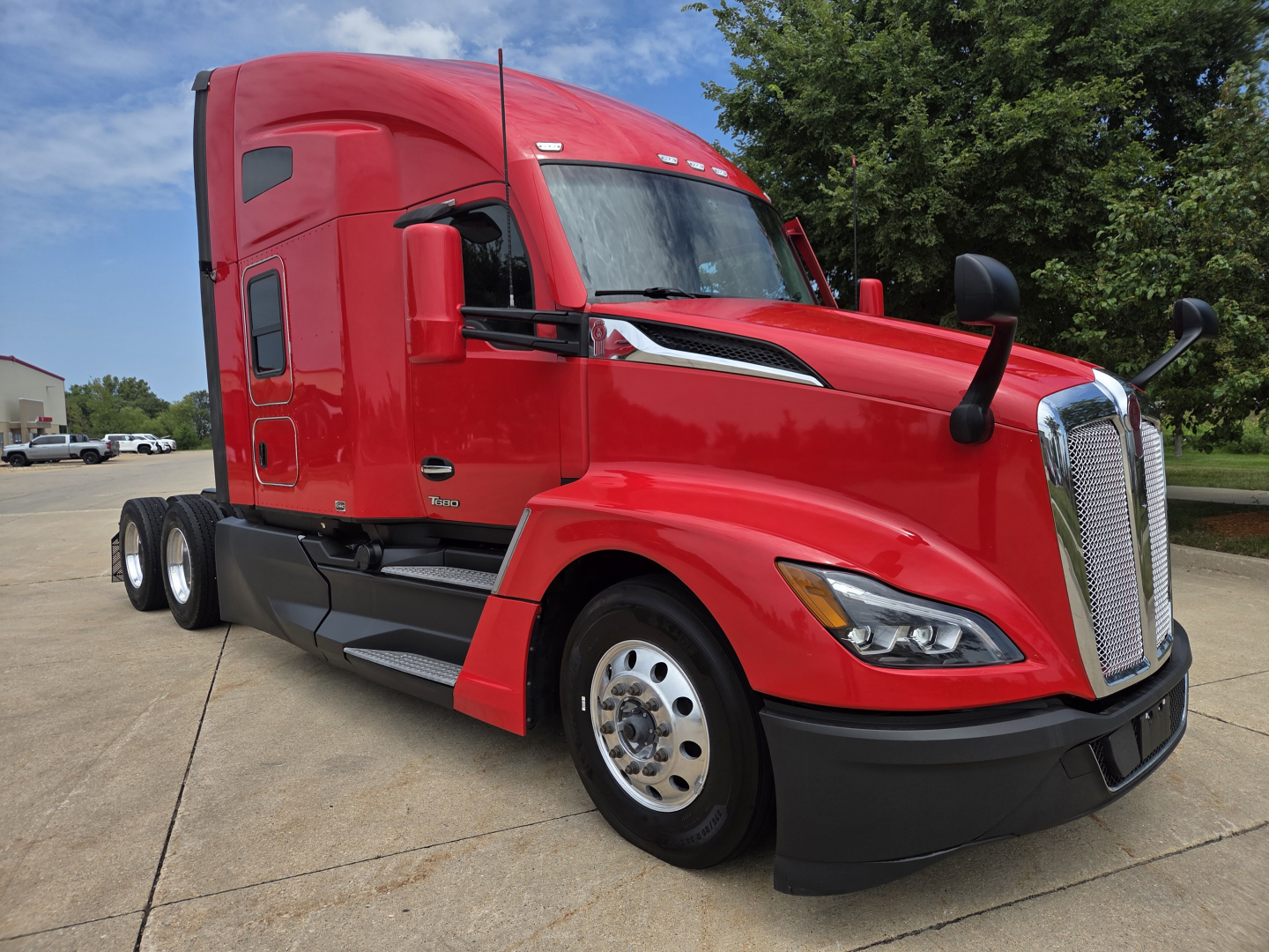 Kenworth T680 tractor-trailer in red, side view showing aerodynamic hood and sleeper cab, no visible text.