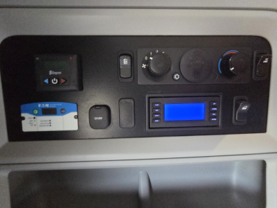 Kenworth T680 dash panel showing control knobs and blue display screen with steering area and card slot.