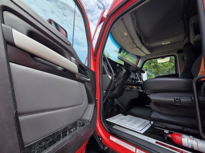 Kenworth T680 truck interior showing driver's seat and open door with dashboard and steering wheel visible.