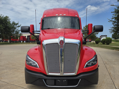 Kenworth T680 front view showing red truck with large chrome grille and black bumper, headlights, and mirrors.