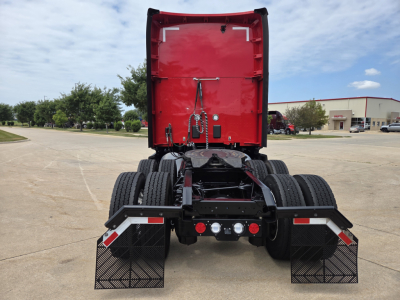 Kenworth T680 rear view showing red sleeper cab rear, dual rear tires, and mud flaps.