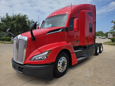 Kenworth T680 tractor in red, front-left angle showing chrome grille, headlights, side mirror, fuel tanks, and chrome wheel covers.