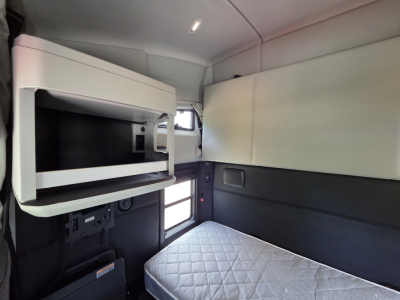 Kenworth T680 sleeper cab interior with bunk and overhead storage shelf visible