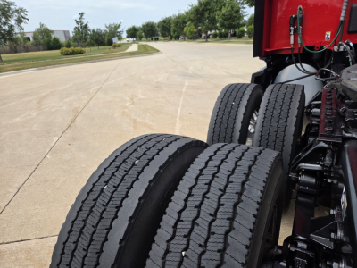 Kenworth T680 trucks showing dual rear axles with tires and red cab body in view.