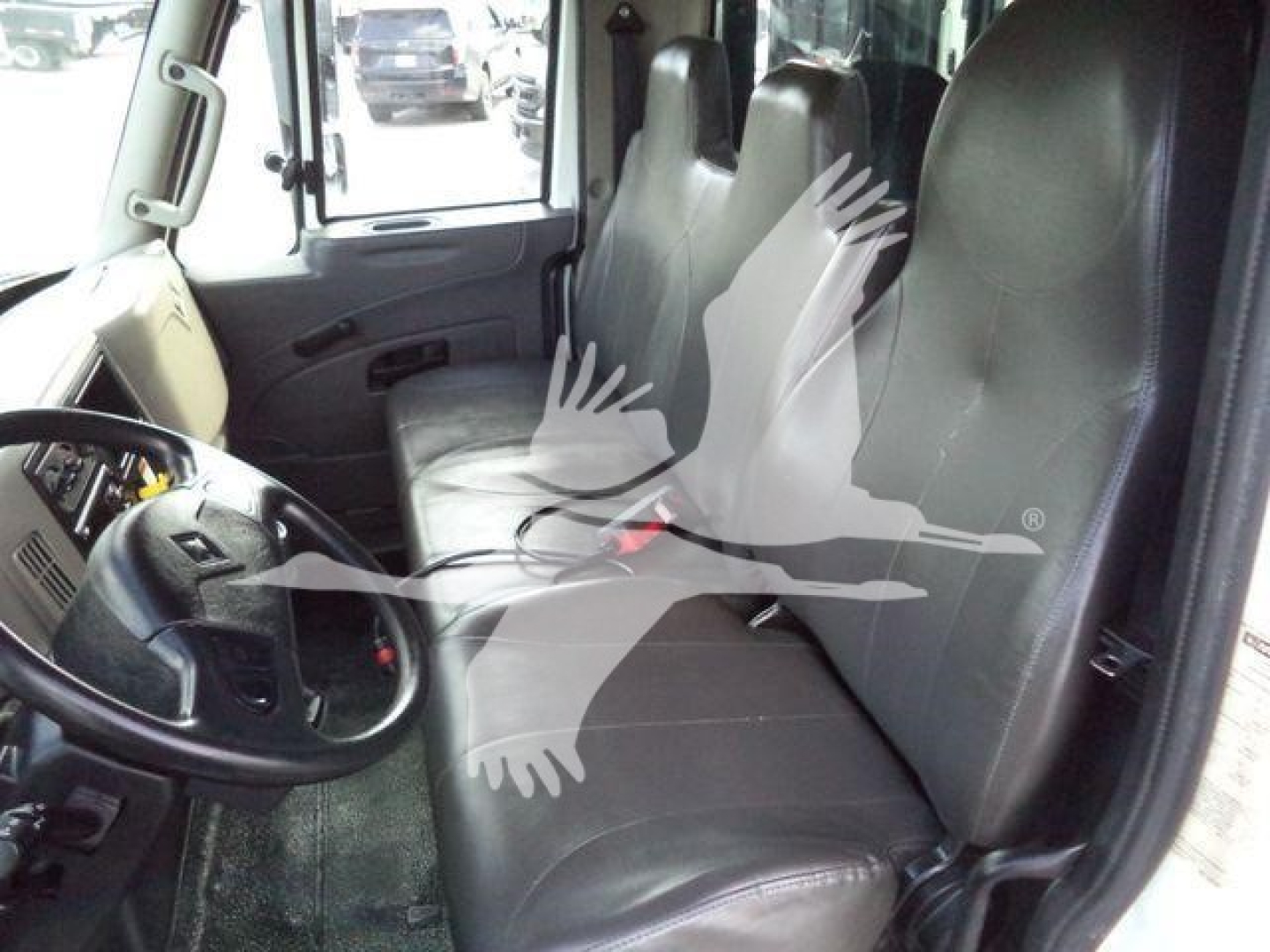Interior of 2019 International Durastar 4300 cab showing driver seat and passenger seating; faint watermark of birds overlaying image.