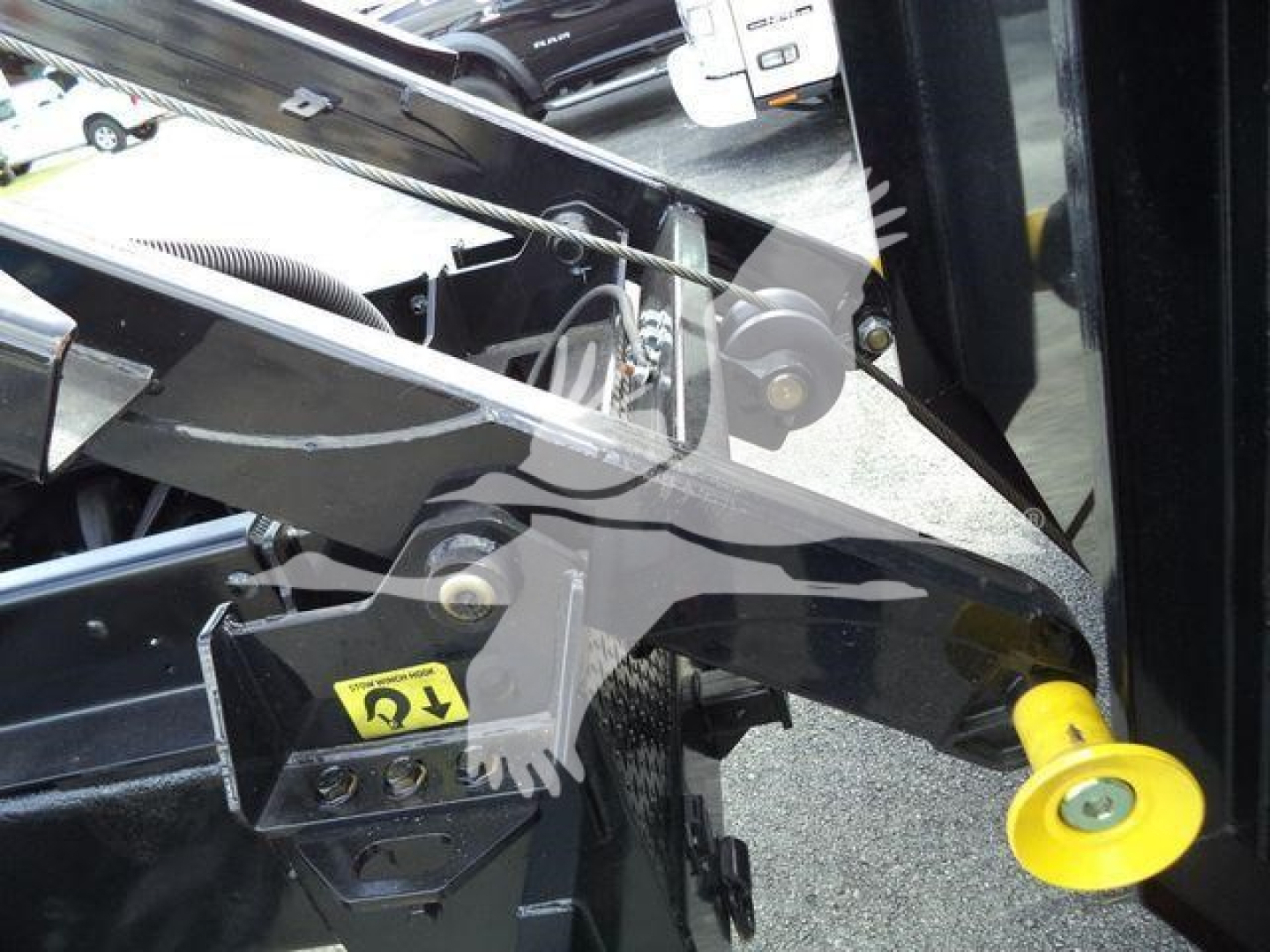 Loader arm of a 2019 International Durastar 4300 roll-off truck showing hydraulic linkage with yellow hitch pin and metal brackets.