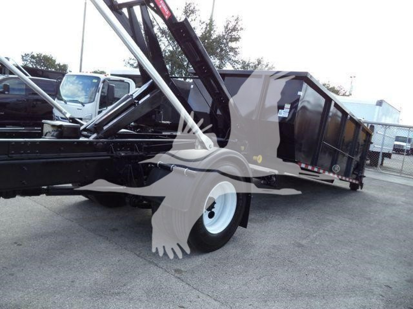 International Durastar 4300 roll-off truck with hydraulic hoist and dumpster bed, side view showing wheel and chassis.