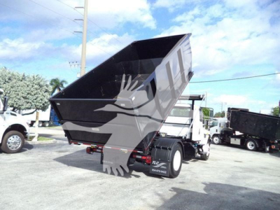 Truck bed in raised position on a 2019 International Durastar 4300 roll-off truck showing dump bed and rear wheels.