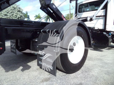 Truck wheel and fender area of a 2019 International Durastar 4300 roll-off truck showing rear tires and hydraulic arm in view.