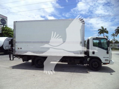 Isuzu NPR HD box truck side view showing large white cargo box on chassis with cab; clear blue sky and palm trees in background