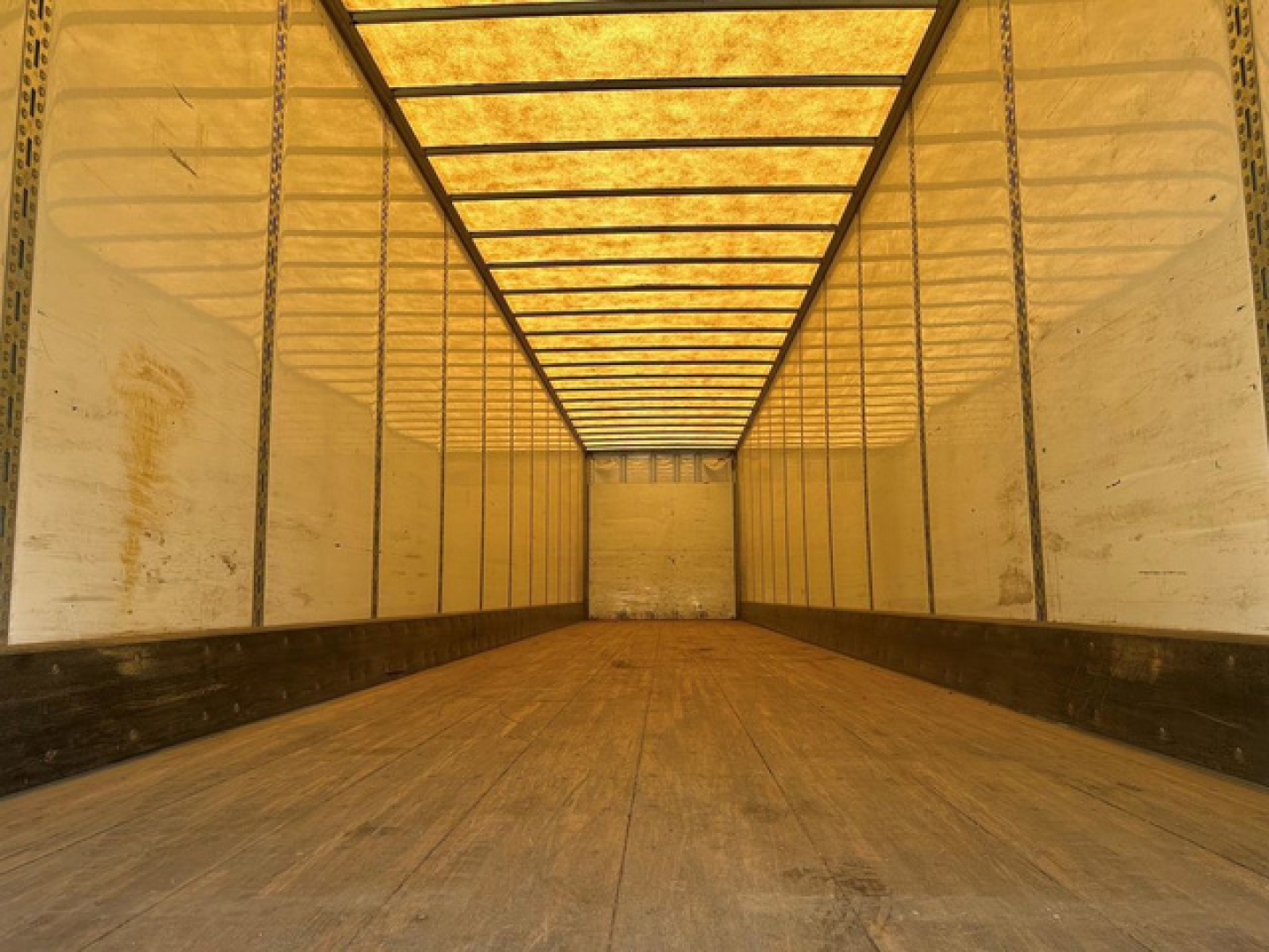 Truck trailer interior showing empty van with wooden floor and side walls, long cargo area