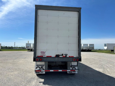 Rear view of a white 2016 Wabash van trailer with closed rear doors, black frame, red and white reflective tape, and bumper with '25' logos visible on mud flaps.