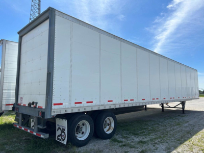 Trailer side view showing a 2016 Wabash van with dual rear axles and white riveted aluminum panels.