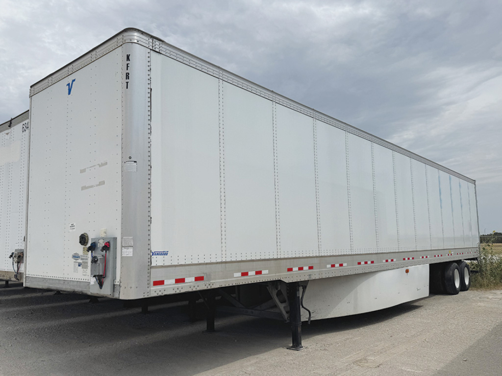 Trailer side view showing a white Vanguard VXP box trailer with dual rear axles and support legs.