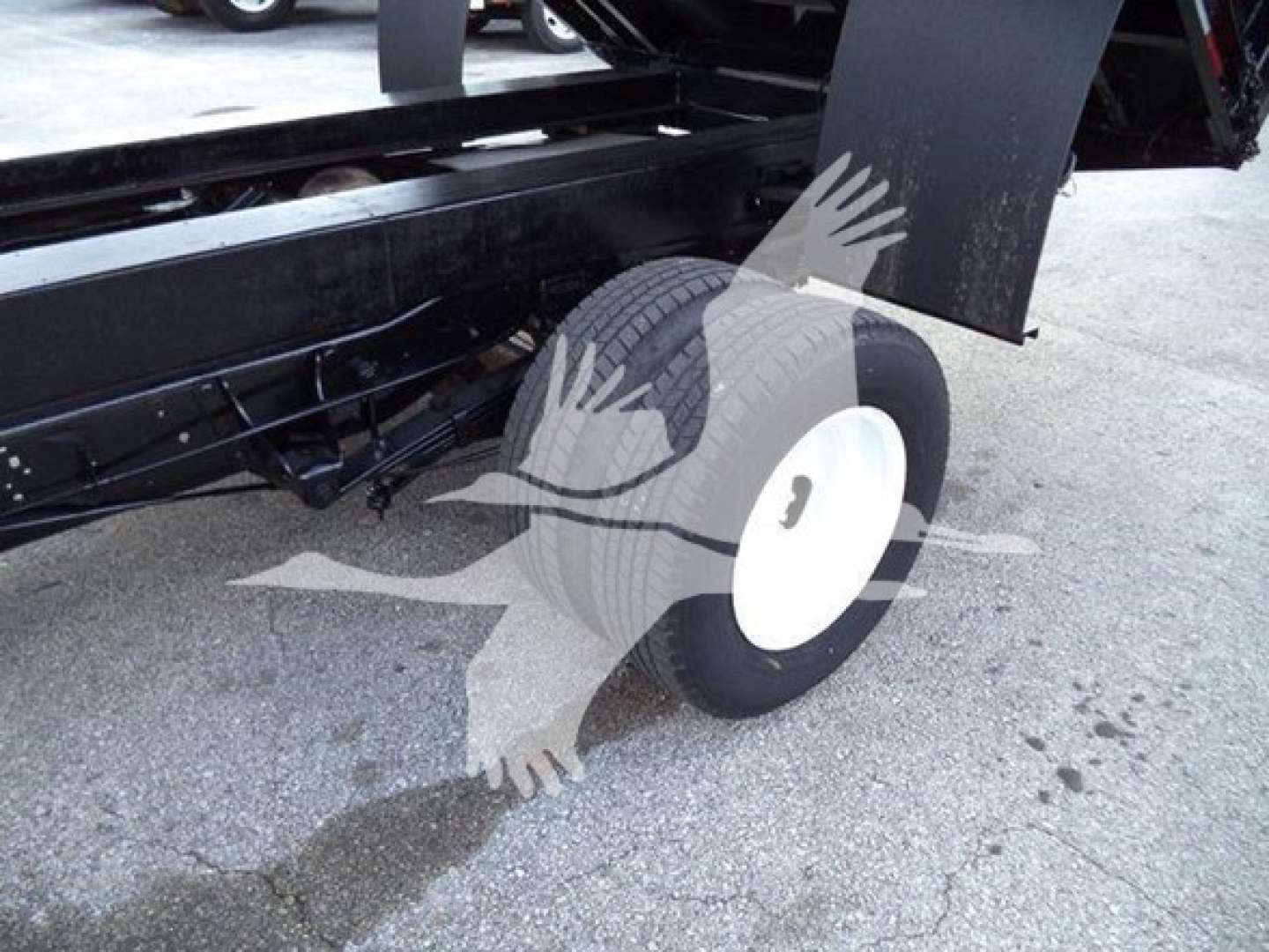 Ford E450 dump truck wheel and undercarriage view showing single rear wheel with white hub, black frame, and metal components.
