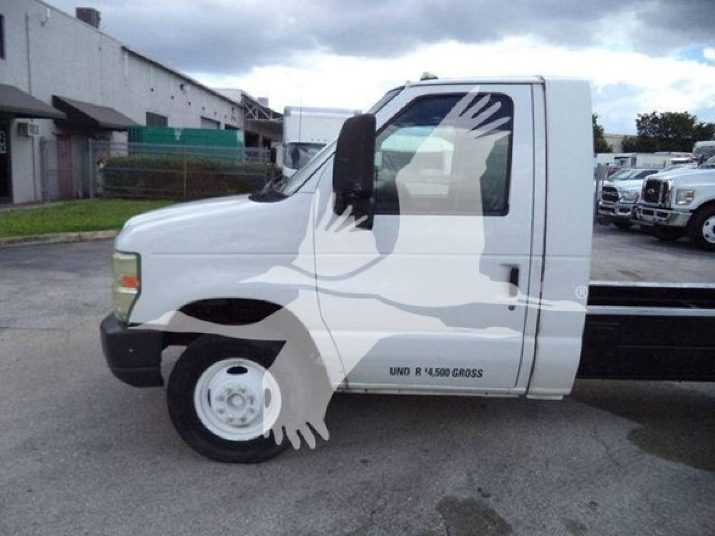 Ford E450 cab and chassis side view showing white body with black bumper and wheel, vented grille, and side badge.