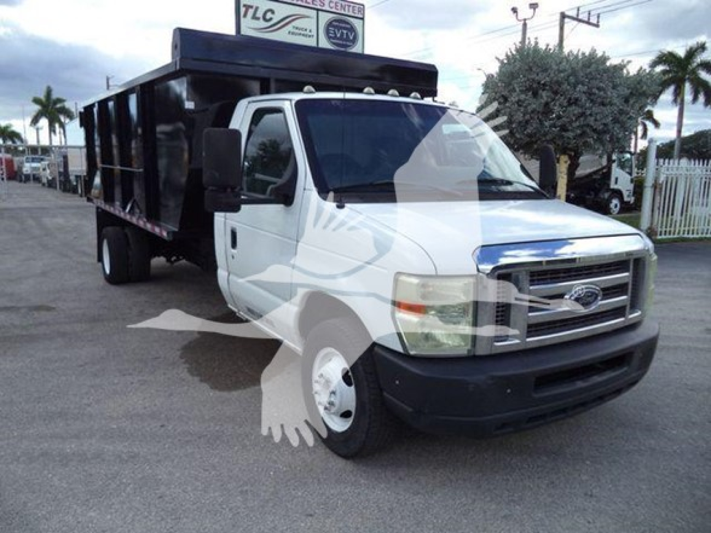 Dump truck with white cab and black dump bed, Ford E450, side view showing front grille and wheel wells.