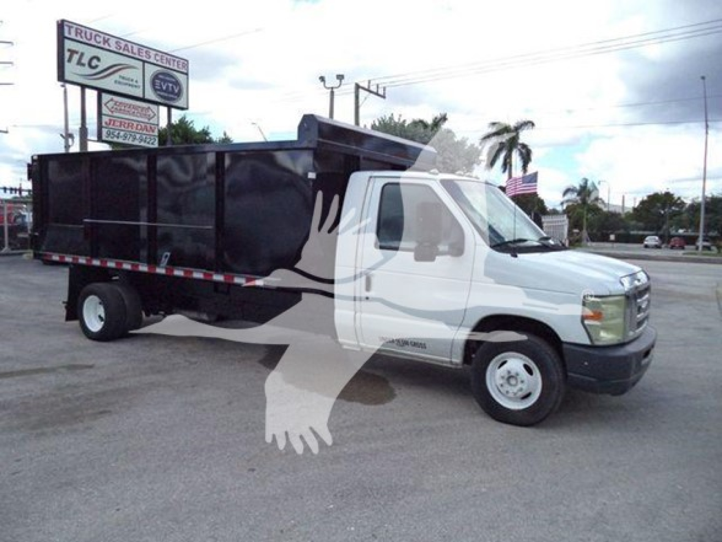 Ford E-450 dump truck in side view with black dump bed and white cab.