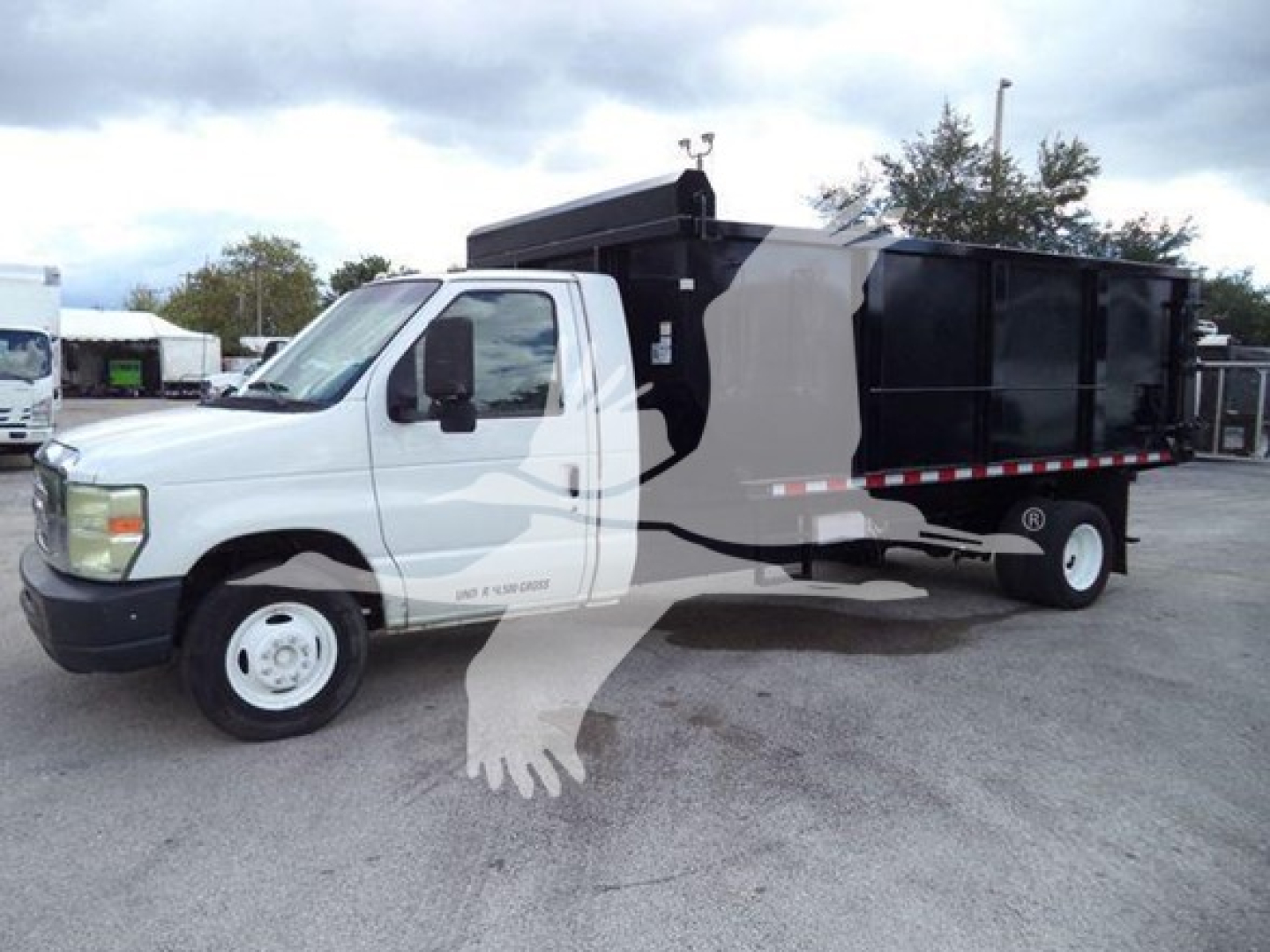 Ford E-450 dump truck in side view with black dump body and white cab, visible text on door and side panels.
