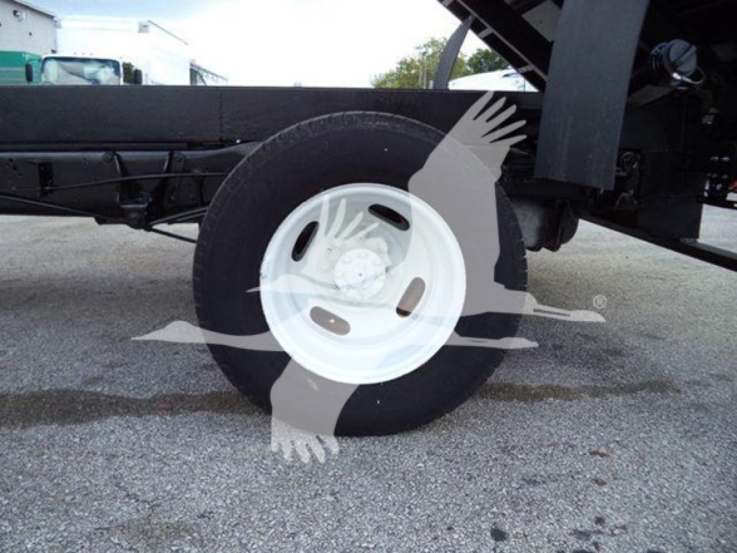 Ford E450 chassis showing wheel and undercarriage of dump truck body with white steel rim.