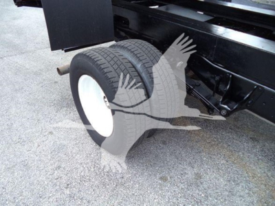 View of rear wheels and suspension on a Ford E450 dump truck chassis. Dual rear tires with white rims. Some undercarriage components visible.