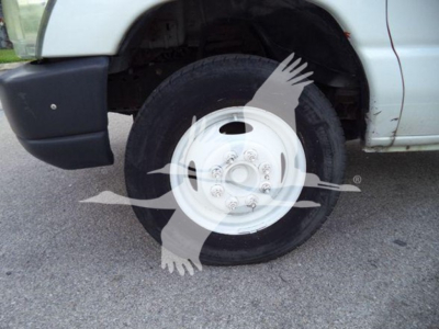 Ford E-Series truck front wheel and fender with white steel wheel and tire, exposed undercarriage slight rust around wheel well area.