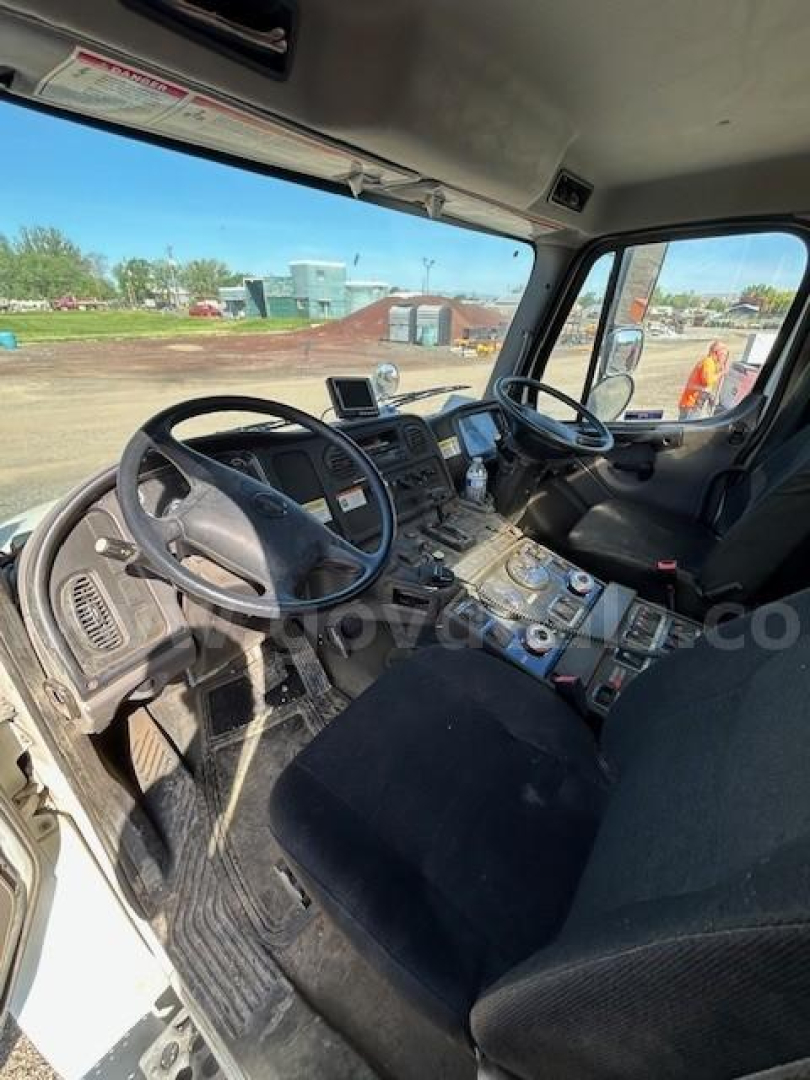 Cab interior of 2012 Freightliner M2 106 sweeper showing steering wheel, dashboard, and center console with controls.
