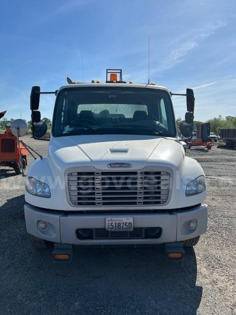 Front view of a white Freightliner M2 106 sweeper truck showing grille, bumper, headlights, and front license plate.