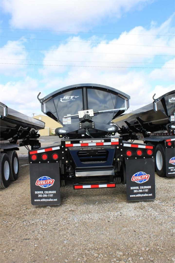 Jet Jetting Systems 2026 Jet Super Spread Side Dump trailer rear view showing dual mudflaps with Utility branding and gravel lot.