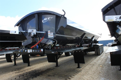 Jet super spread side dump trailer showing Gooseneck hitch and hydraulic system with Jet logo on side panel.