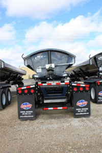 Jet Jetting Systems 2026 Jet Super Spread Side Dump trailer rear view showing dual mudflaps with Utility branding and gravel lot.