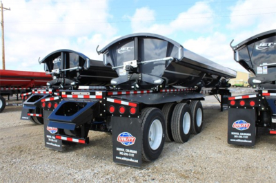 Jet Tri Axle Super Spread Side Dump trailer showing dual rear dumps with black hoppers and triple-axle wheels, reflective tape, and mud flaps.