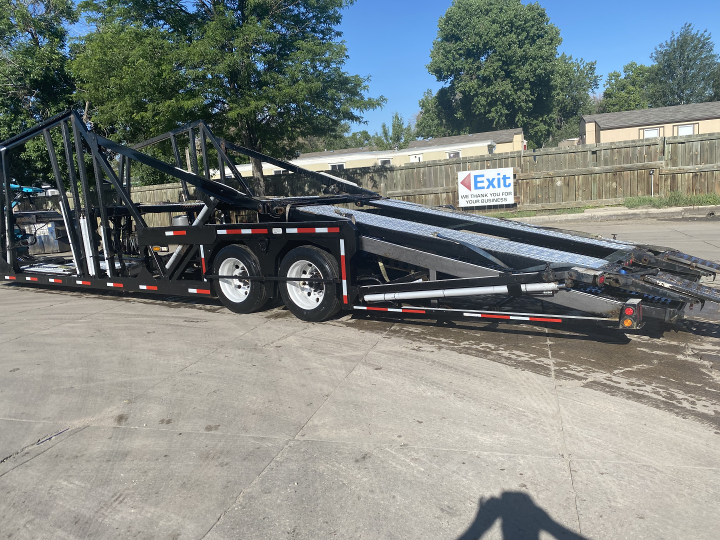 2019 Peterbilt 389 auto carrier trailer in a lot with dual-axle staging, black frame, with folded bed sections and ramps visible.