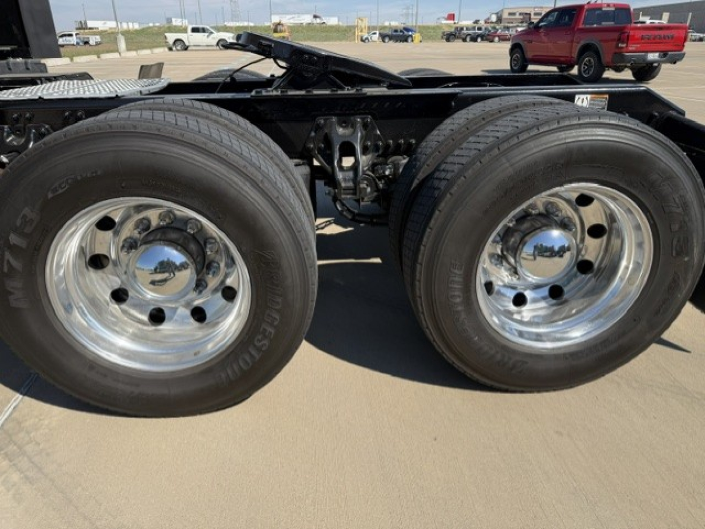 Dual rear axles of a Kenworth truck chassis showing chrome wheels and tires, with undercarriage and suspension components visible.