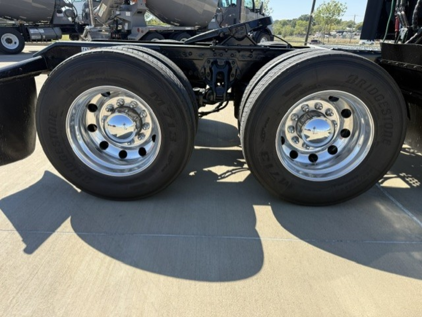 Dual rear wheels on a Kenworth truck chassis showing chrome hubcaps and tires with Bridgestone branding.