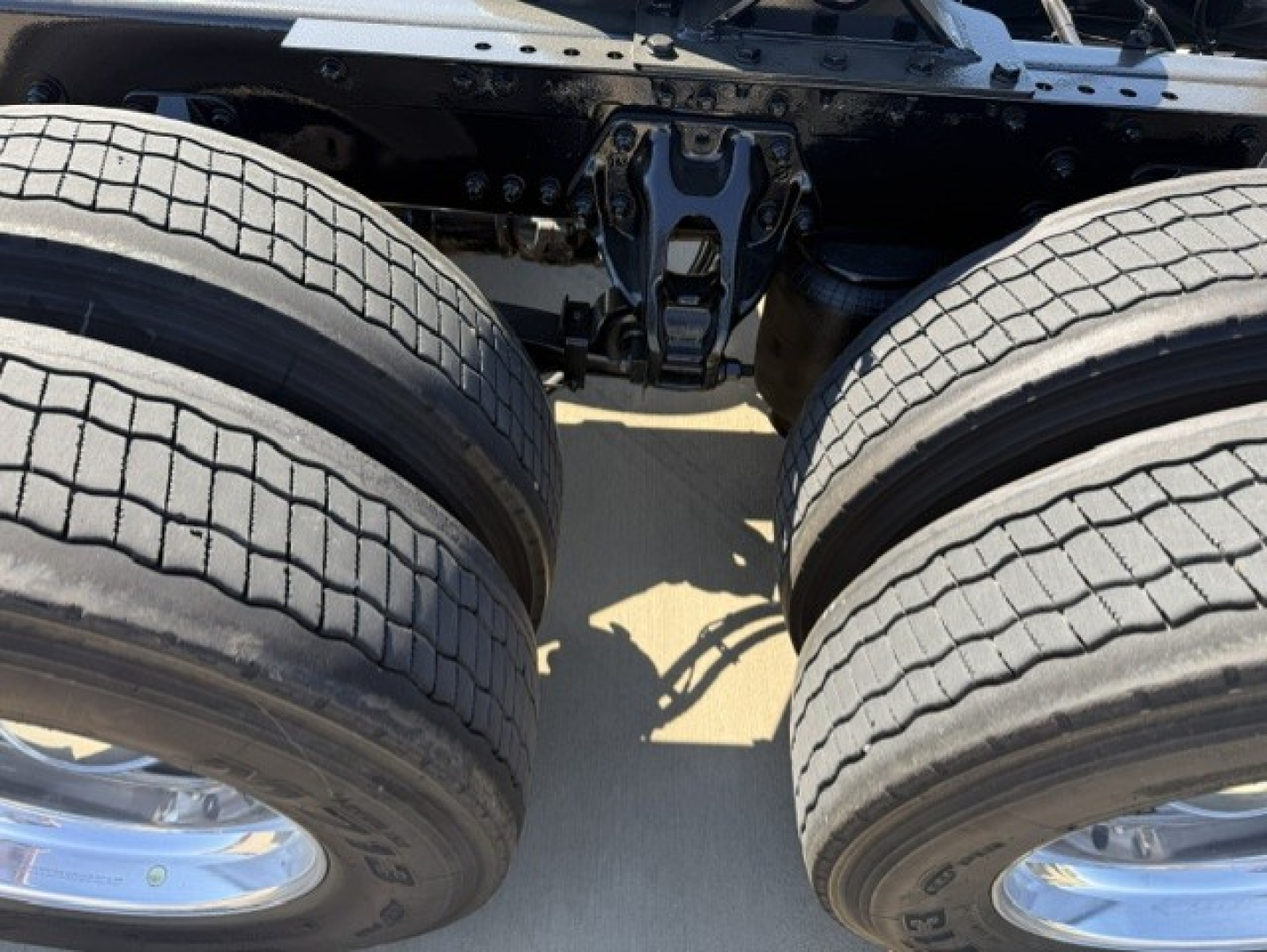 Dual rear wheels of a Kenworth truck chassis showing suspension and tire treads.