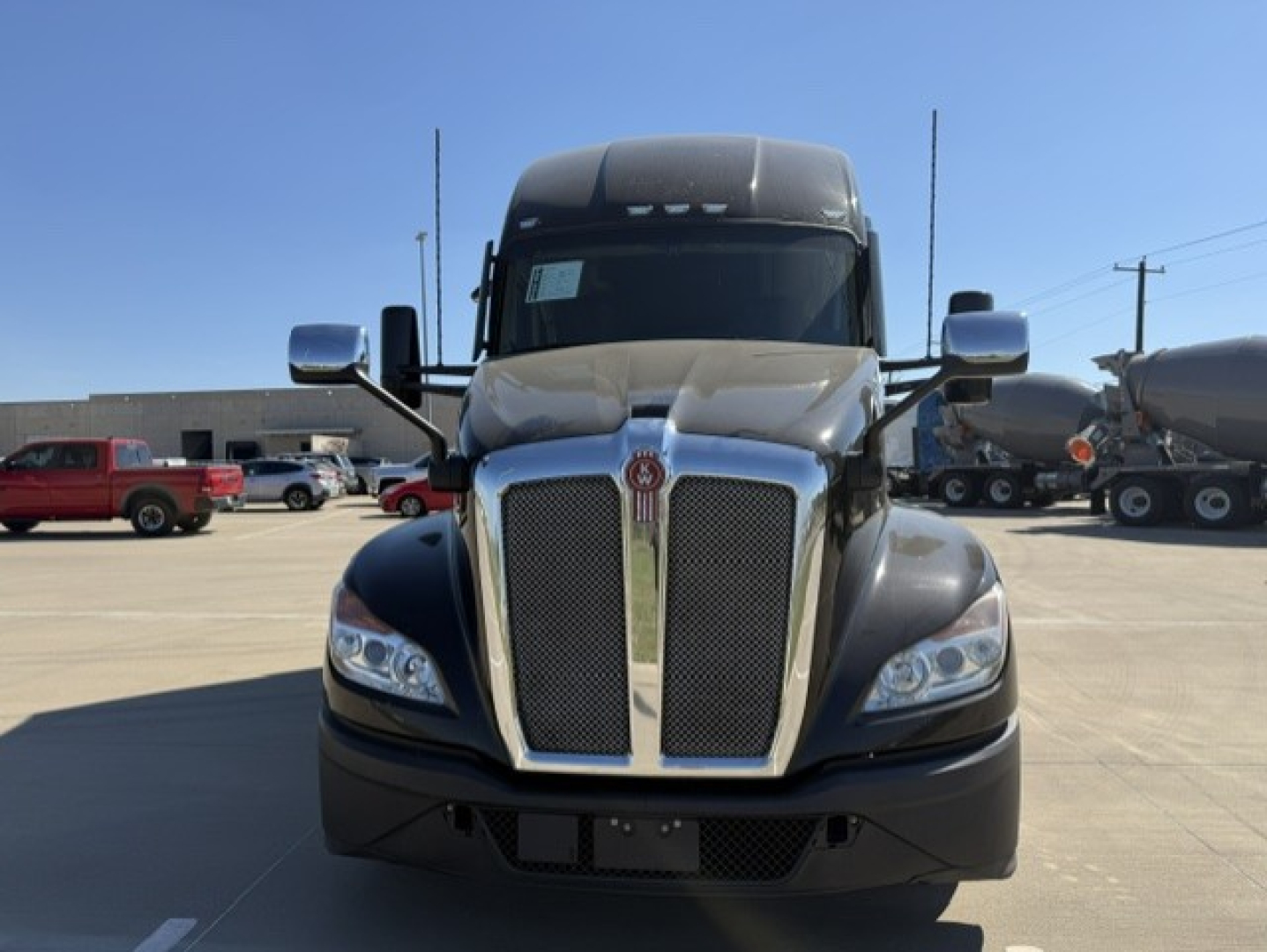 Kenworth T680 front view showing chrome grille and headlights in a parking lot.