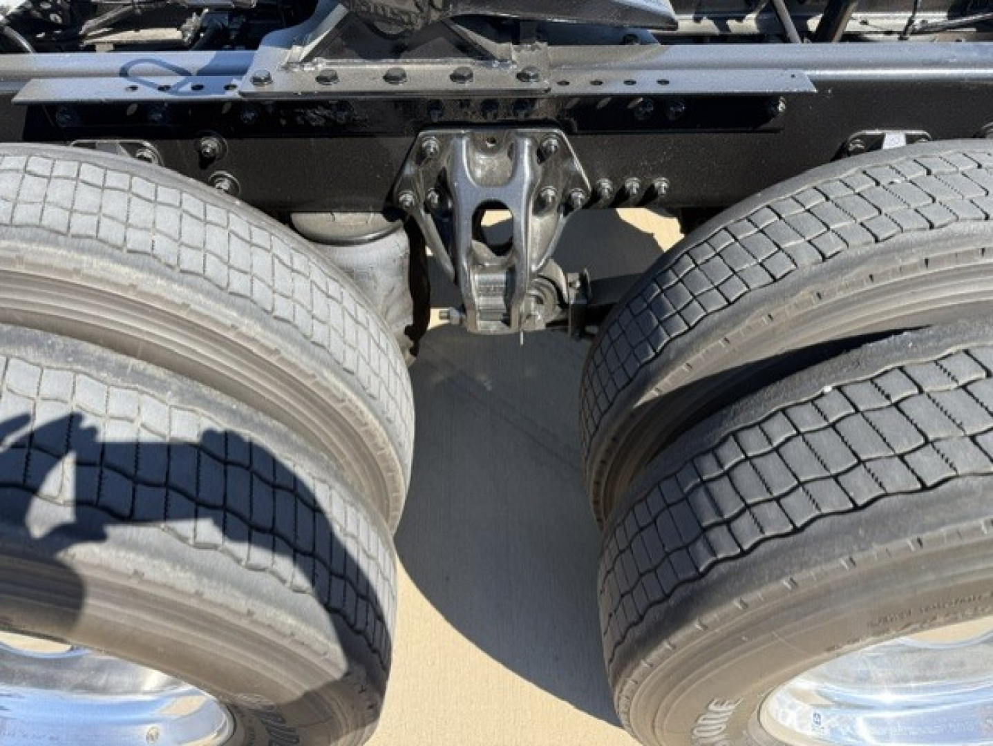 Kenworth truck rear view showing tandem axle suspension and dual tires.