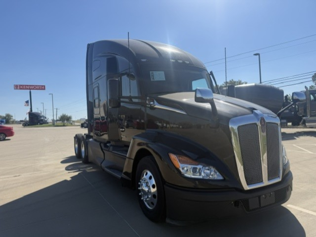 Kenworth T680 tractor in a dealership lot, glossy black with chrome grille, front-left view